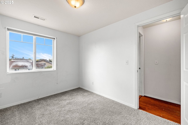 carpeted empty room with visible vents and baseboards
