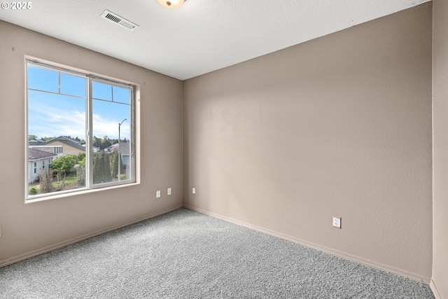carpeted empty room featuring baseboards and visible vents