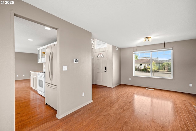 unfurnished living room with recessed lighting, baseboards, and light wood-style floors