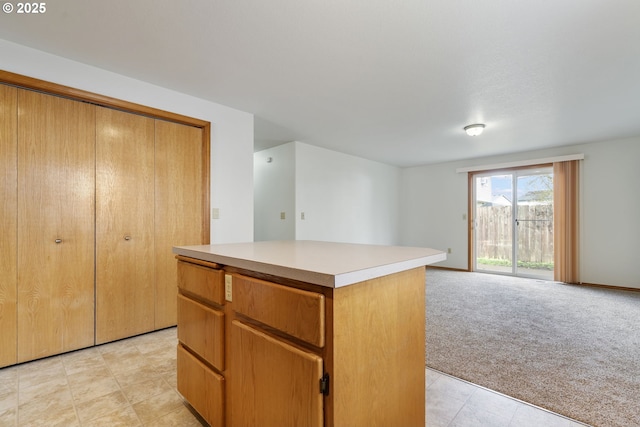 kitchen featuring a kitchen island, open floor plan, light countertops, and light colored carpet