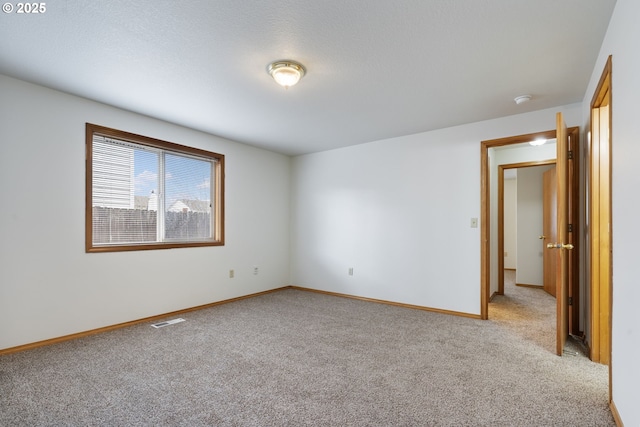 unfurnished room with light carpet, baseboards, visible vents, and a textured ceiling