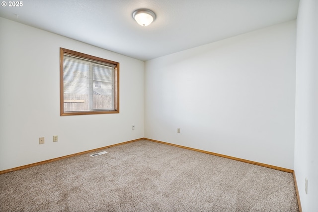 spare room featuring carpet, visible vents, and baseboards