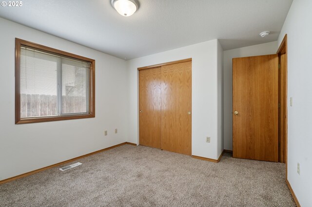 unfurnished bedroom featuring carpet floors, a closet, visible vents, and baseboards