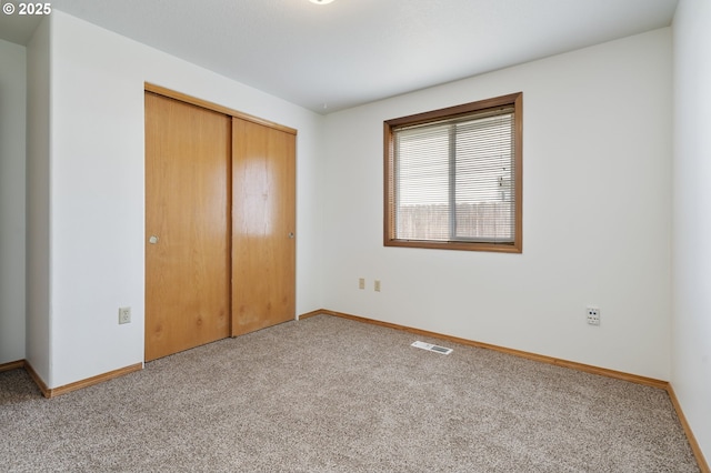 unfurnished bedroom with carpet floors, a closet, visible vents, and baseboards