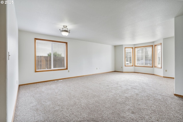 unfurnished room featuring baseboards, a textured ceiling, and carpet flooring