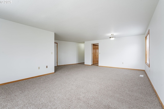 spare room featuring baseboards and light colored carpet