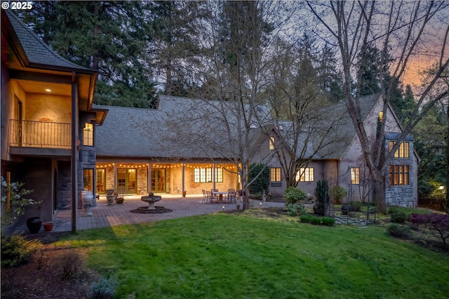 1500 SE Waverly Dr, Milwaukie, OR 97222 - back of house at dusk with a patio, a yard, a shingled roof, and stucco siding