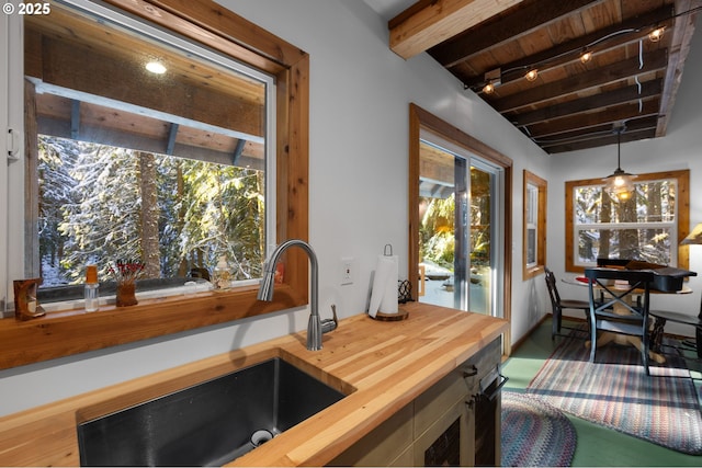 interior space with beam ceiling, sink, wooden ceiling, wooden counters, and pendant lighting