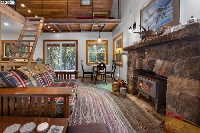 living room featuring carpet floors, beamed ceiling, wood ceiling, and a stone fireplace