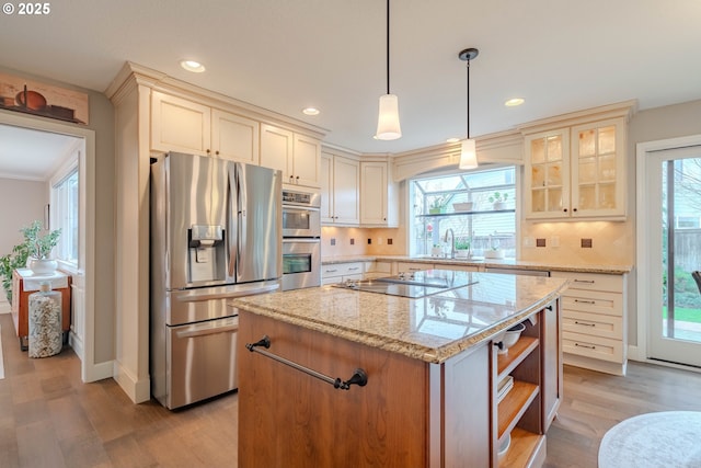 kitchen featuring sink, light stone counters, a center island, appliances with stainless steel finishes, and pendant lighting