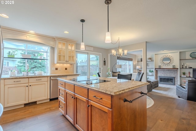 kitchen with sink, decorative light fixtures, a center island, stainless steel dishwasher, and black electric stovetop