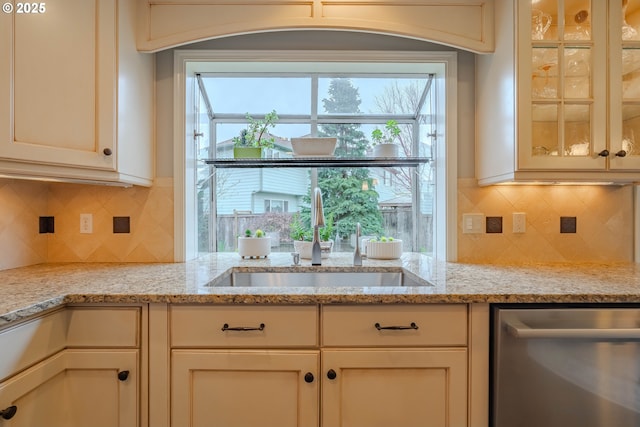 kitchen featuring light stone countertops, sink, stainless steel dishwasher, and backsplash