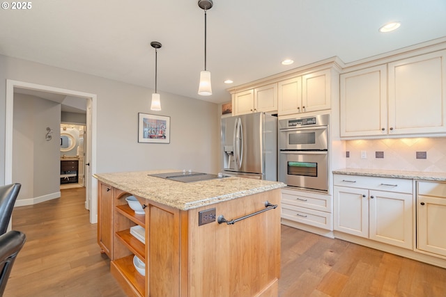 kitchen featuring light stone counters, stainless steel appliances, hanging light fixtures, and a center island with sink