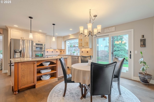 dining space featuring sink, a notable chandelier, and wood-type flooring