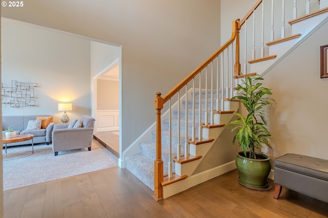 staircase featuring wood-type flooring and a high ceiling