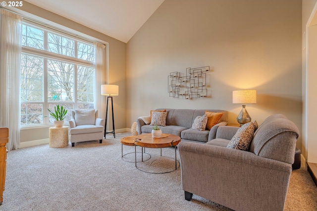 carpeted living room with high vaulted ceiling