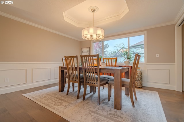 dining room featuring crown molding, wood-type flooring, a tray ceiling, and a chandelier