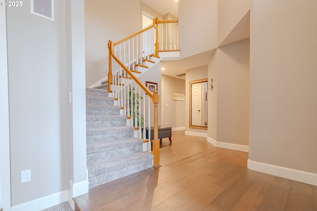 staircase with hardwood / wood-style flooring and a high ceiling