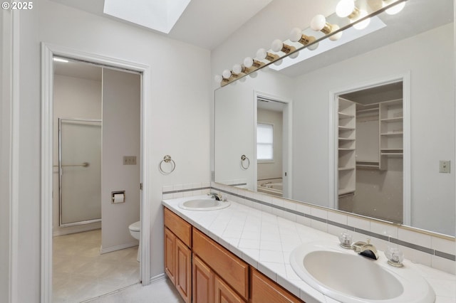 bathroom featuring vanity, a skylight, tasteful backsplash, and toilet