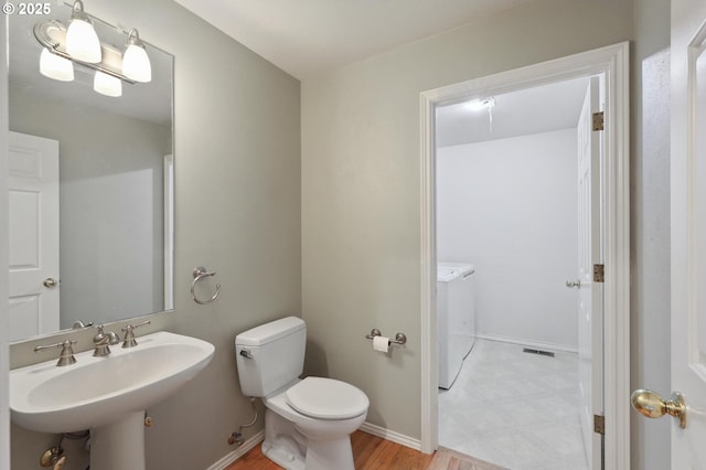 bathroom with separate washer and dryer, sink, and toilet