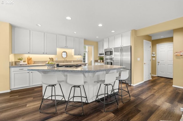 kitchen featuring a kitchen breakfast bar, appliances with stainless steel finishes, and white cabinetry