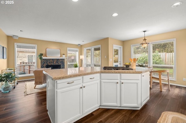 kitchen featuring stainless steel gas stovetop, dark wood finished floors, a fireplace, and white cabinets