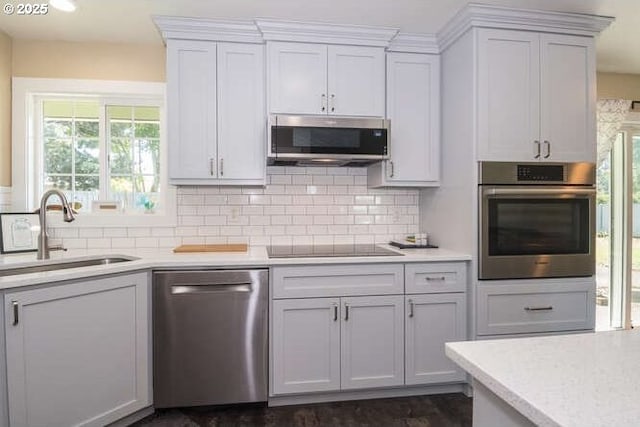 kitchen featuring appliances with stainless steel finishes, a sink, light countertops, and backsplash