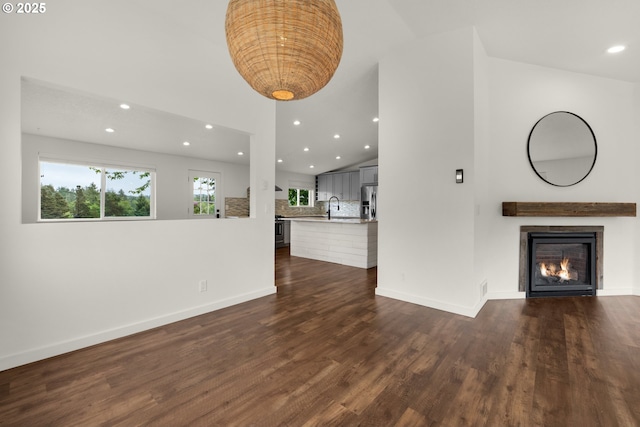 657 Summit Ave, Gearhart, OR 97138 - unfurnished living room featuring recessed lighting, a warm lit fireplace, dark wood-style flooring, a sink, and baseboards