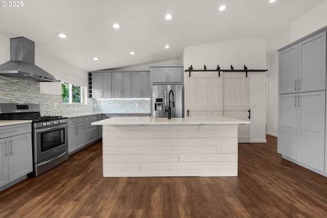 657 Summit Ave, Gearhart, OR 97138 - kitchen with stainless steel appliances, exhaust hood, gray cabinetry, a center island with sink, and decorative backsplash