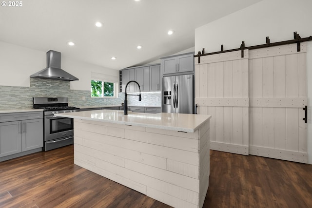 657 Summit Ave, Gearhart, OR 97138 - kitchen featuring appliances with stainless steel finishes, wall chimney range hood, gray cabinetry, decorative backsplash, and dark wood-style flooring