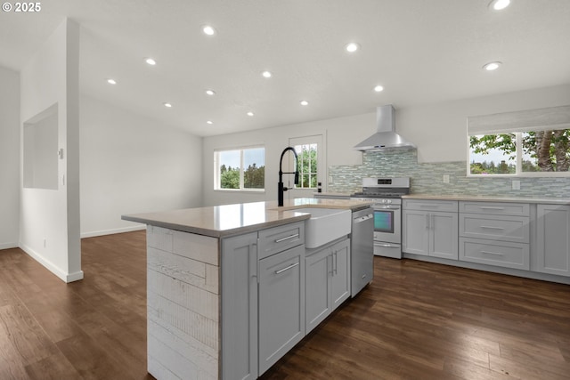 657 Summit Ave, Gearhart, OR 97138 - kitchen featuring wall chimney exhaust hood, stainless steel appliances, a sink, backsplash, and dark wood-type flooring