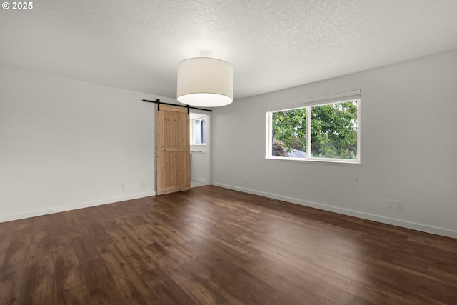 657 Summit Ave, Gearhart, OR 97138 - unfurnished room with a barn door, dark wood finished floors, baseboards, and a textured ceiling