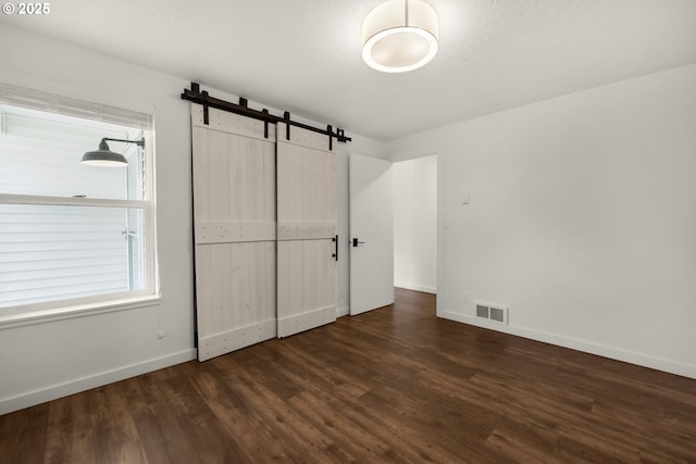 657 Summit Ave, Gearhart, OR 97138 - unfurnished bedroom with wood finished floors, baseboards, and a barn door