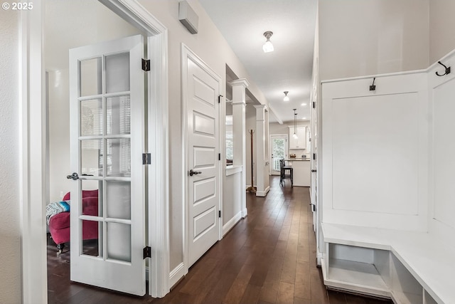 hallway with dark wood-type flooring and decorative columns