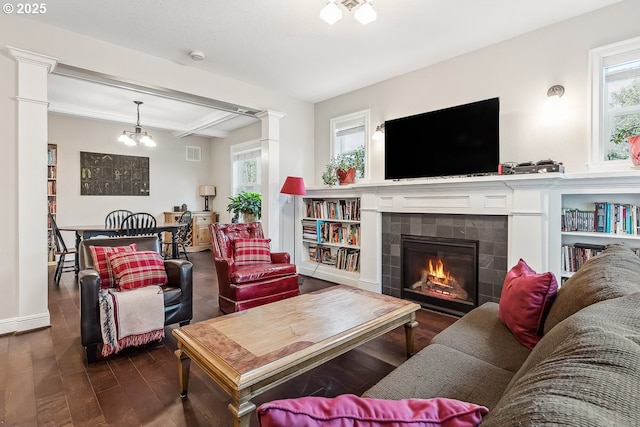 living room featuring hardwood / wood-style flooring, plenty of natural light, a tile fireplace, and decorative columns