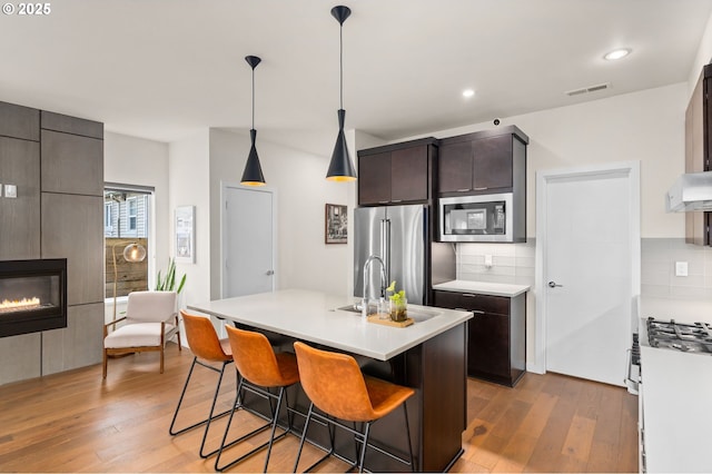 kitchen with a center island with sink, a breakfast bar, stainless steel appliances, and backsplash