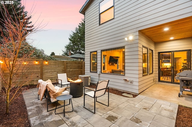 patio terrace at dusk featuring central AC unit and an outdoor fire pit