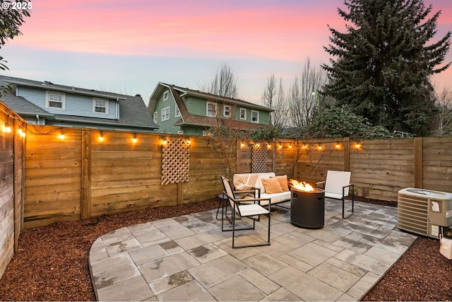 patio terrace at dusk featuring central AC and an outdoor fire pit