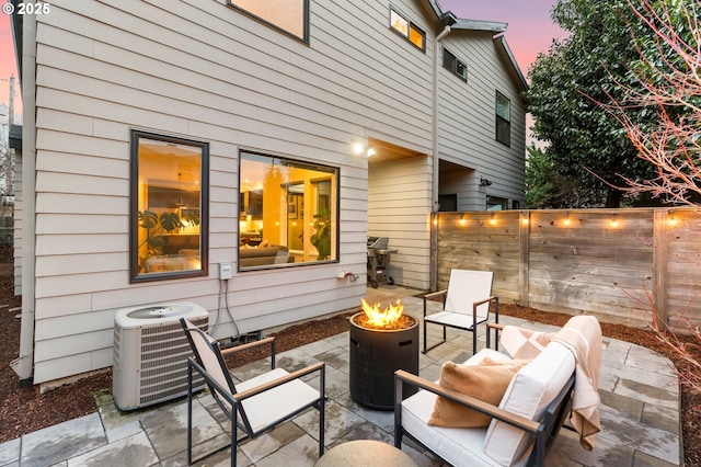 patio terrace at dusk with an outdoor fire pit, area for grilling, and cooling unit