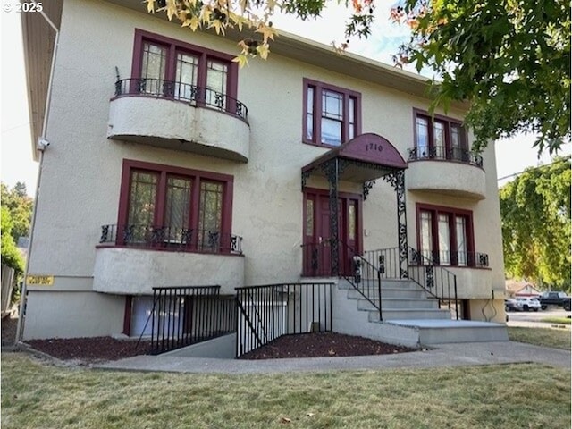 view of front of home with a balcony and stucco siding