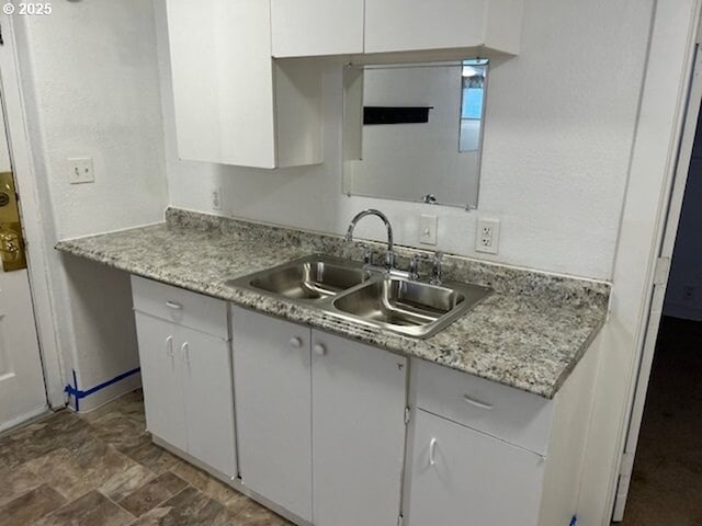 kitchen featuring stone finish floor, white cabinets, light countertops, and a sink