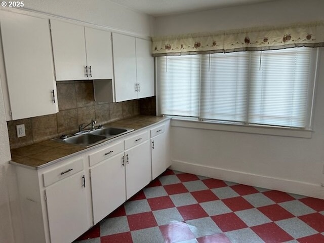 kitchen featuring white cabinetry, a sink, baseboards, and tile patterned floors