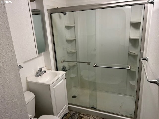 full bath with a stall shower, vanity, and toilet