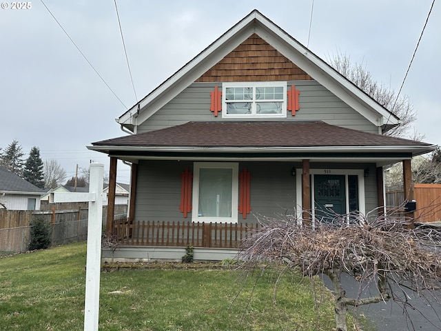 bungalow-style home with a porch, a shingled roof, a front yard, and fence