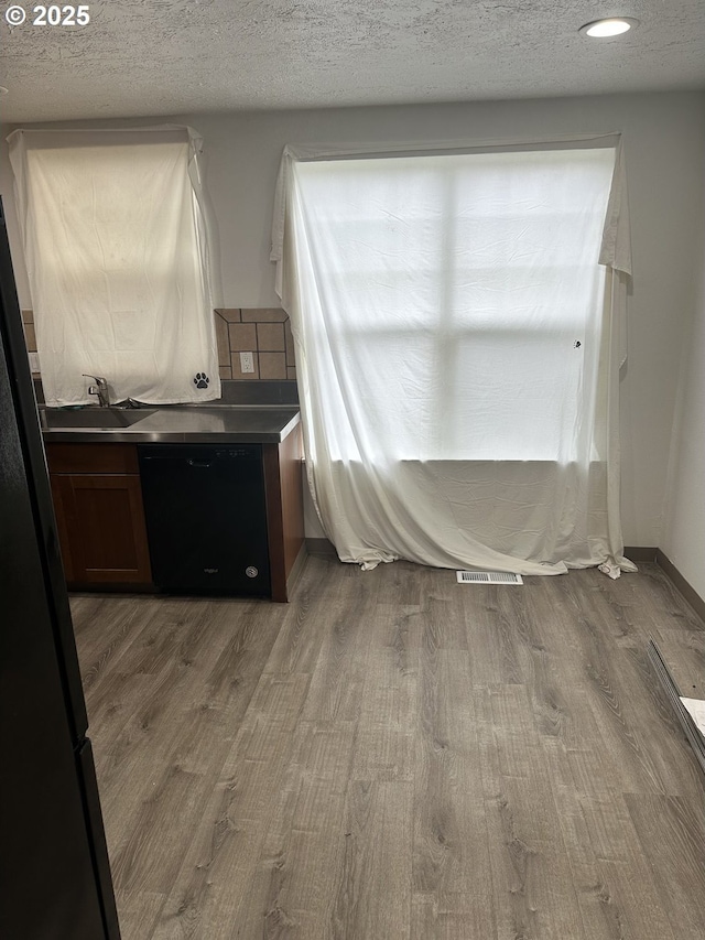 interior space with wood finished floors, visible vents, freestanding refrigerator, a sink, and a textured ceiling