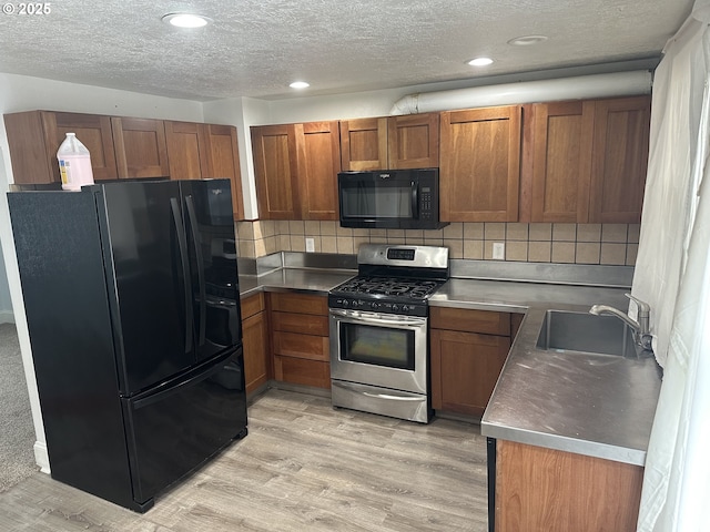 kitchen with black appliances, light wood-type flooring, brown cabinets, and a sink