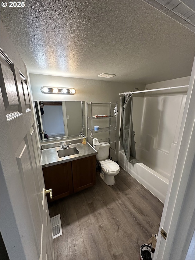 full bath featuring shower / bath combo with shower curtain, toilet, a textured ceiling, wood finished floors, and vanity