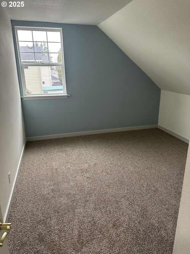 bonus room with lofted ceiling, baseboards, carpet floors, and a textured ceiling