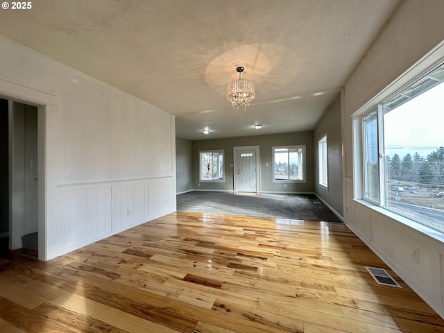 interior space featuring a textured ceiling, a notable chandelier, and light hardwood / wood-style floors