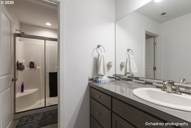 bathroom with vanity, a shower stall, and visible vents